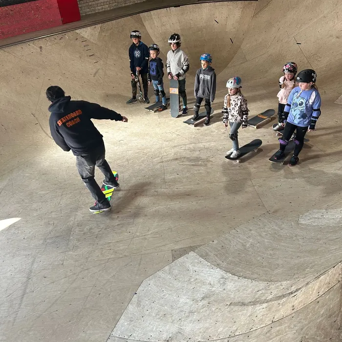 Coach Pye dropping in while kids watch from the lip of the bowl at Prevail Skatehouse
