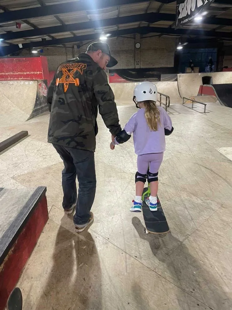 Coach Rich guiding a young skater on her board at Prevail Skatehouse